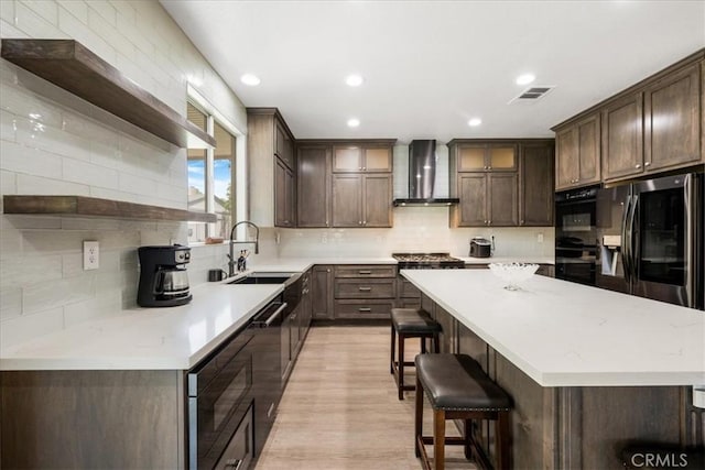 19454 Copper Ridge St, Perris, CA 92570 - kitchen with wall chimney exhaust hood, open shelves, black appliances, dark brown cabinetry, and a center island