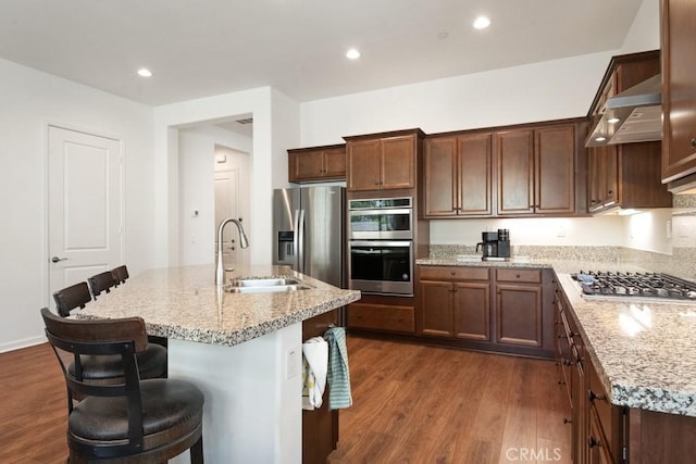 24190 Evesong Dr, Corona, CA 92883 - kitchen with stainless steel appliances, dark wood finished floors, light stone counters, a center island with sink, and recessed lighting