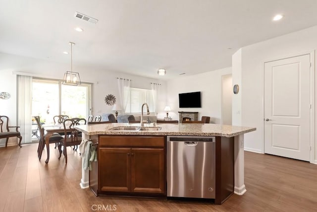24190 Evesong Dr, Corona, CA 92883 - kitchen with stainless steel dishwasher, a sink, an island with sink, light stone countertops, and dark wood-style floors