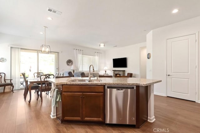 24190 Evesong Dr, Corona, CA 92883 - kitchen featuring stainless steel dishwasher, a center island with sink, dark wood-type flooring, light stone countertops, and open floor plan