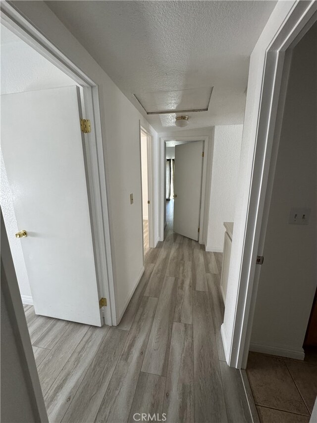 3178 Dogwood Dr, Corona, CA 92882 - hallway with wood finished floors, a textured ceiling, and attic access