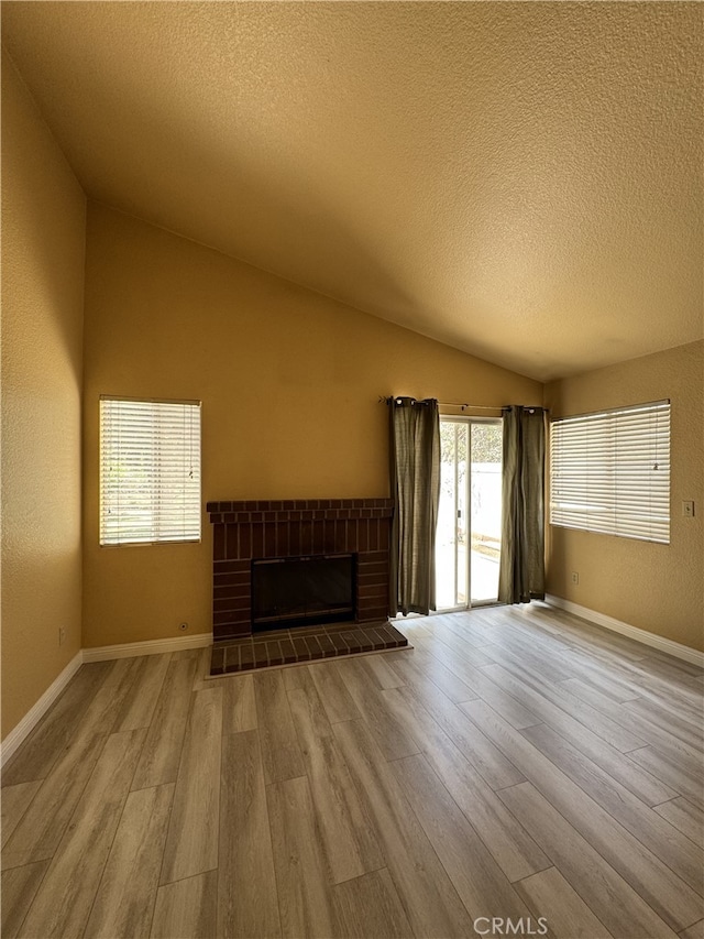 3178 Dogwood Dr, Corona, CA 92882 - unfurnished living room with wood finished floors, vaulted ceiling, a textured ceiling, a fireplace with raised hearth, and baseboards
