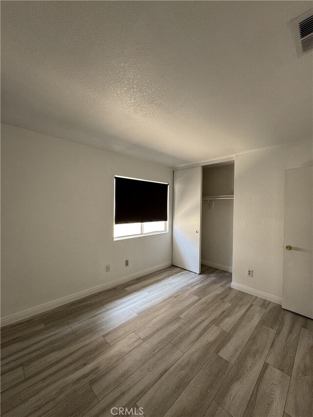 3178 Dogwood Dr, Corona, CA 92882 - unfurnished bedroom featuring wood finished floors, a textured ceiling, baseboards, and a closet