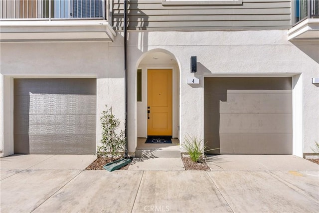 94231/2 N Sepulveda Blvd Unit 4, North Hills, CA 91343 - property entrance with an attached garage, stucco siding, concrete driveway, and a balcony
