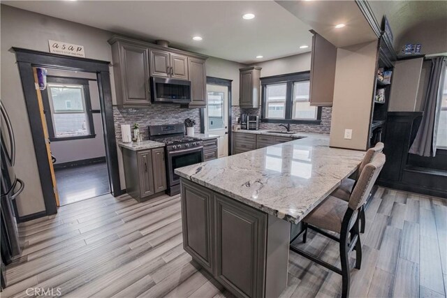 5837 Esperanza Ave, Whittier, CA 90606 - kitchen with stainless steel appliances, a breakfast bar area, light wood finished floors, a sink, and light stone countertops