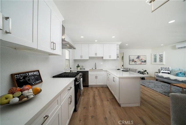 3037 Pacific Ave, Long Beach, CA 90806 - kitchen featuring gas range, a sink, a peninsula, wall chimney range hood, and an AC wall unit