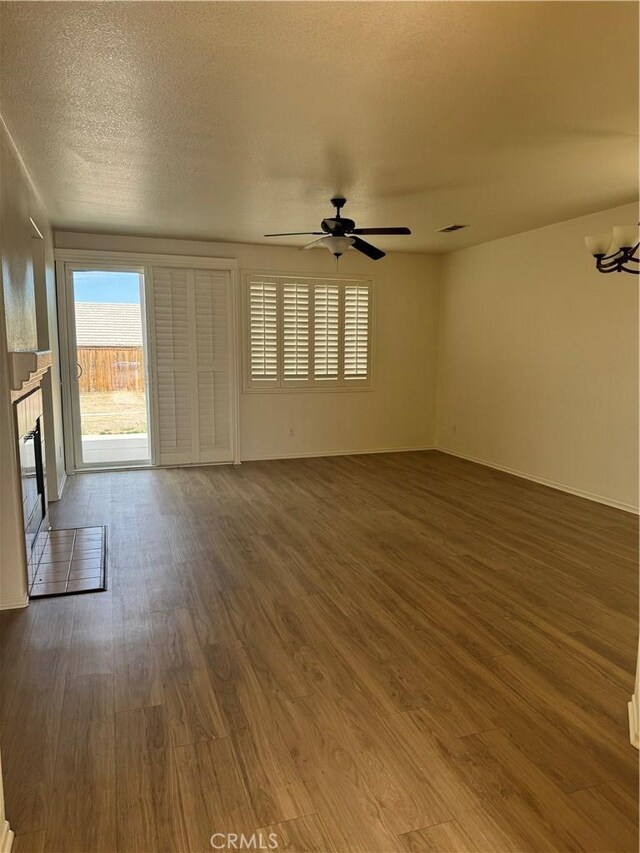 14543 Handsdale St, Adelanto, CA 92301 - unfurnished living room featuring dark wood-style flooring, a ceiling fan, a tile fireplace, a chandelier, and baseboards