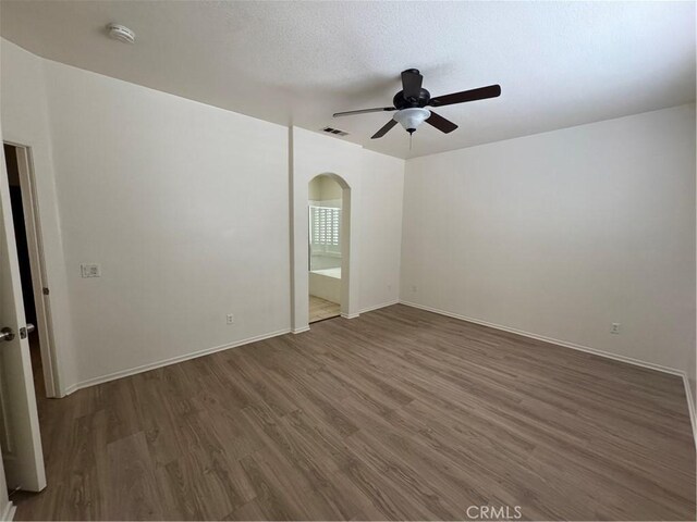 14543 Handsdale St, Adelanto, CA 92301 - unfurnished room with a smoke detector, ceiling fan, wood finished floors, arched walkways, and baseboards