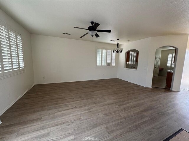 14543 Handsdale St, Adelanto, CA 92301 - empty room with a ceiling fan, arched walkways, a chandelier, wood finished floors, and baseboards