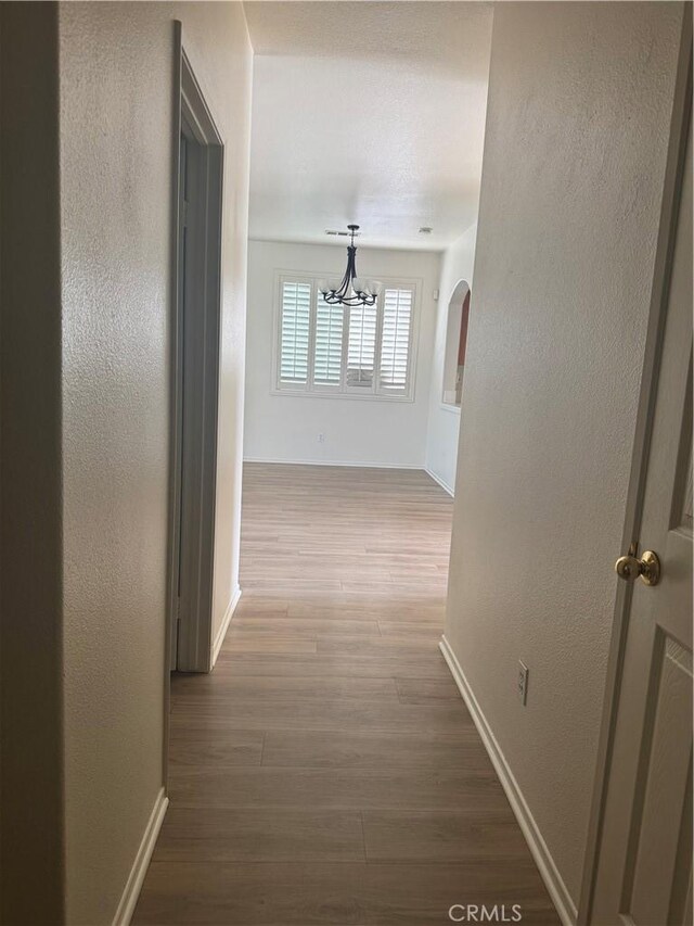 14543 Handsdale St, Adelanto, CA 92301 - corridor with a chandelier, baseboards, wood finished floors, and a textured wall