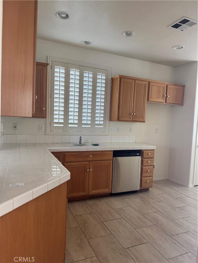 14543 Handsdale St, Adelanto, CA 92301 - kitchen featuring dishwasher, brown cabinetry, tile counters, recessed lighting, and a sink