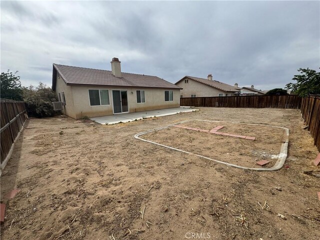 14543 Handsdale St, Adelanto, CA 92301 - rear view of house with a patio area, a fenced backyard, a chimney, stucco siding, and a tiled roof