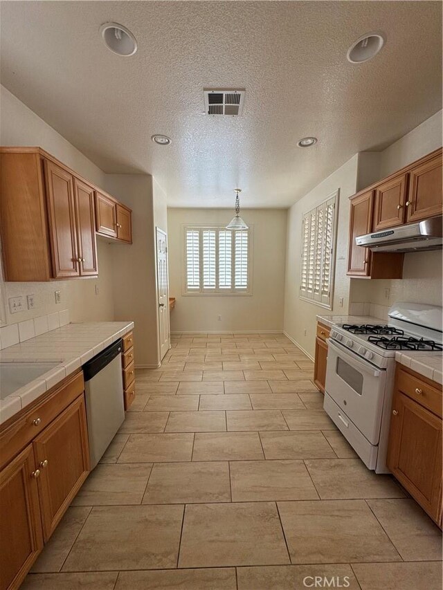 14543 Handsdale St, Adelanto, CA 92301 - kitchen featuring gas range gas stove, stainless steel dishwasher, tile countertops, under cabinet range hood, and a textured ceiling