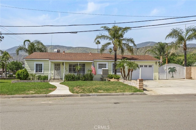 4909 Sepulveda Ave, San Bernardino, CA 92404 - ranch-style home with a gate, concrete driveway, an attached garage, a mountain view, and a porch