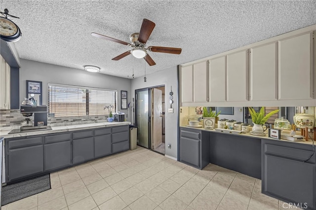 4909 Sepulveda Ave, San Bernardino, CA 92404 - kitchen with light countertops, gray cabinetry, ceiling fan, a textured ceiling, and tasteful backsplash
