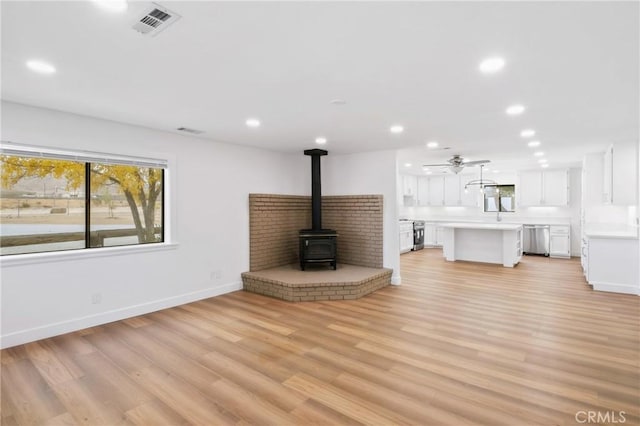14040 Oden Dr, Apple Valley, CA 92307 - unfurnished living room with a wood stove, recessed lighting, plenty of natural light, baseboards, and ceiling fan