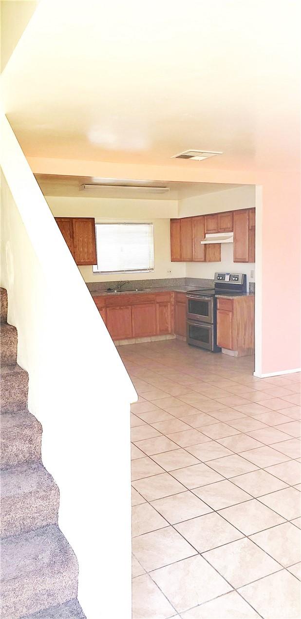 517 Lincoln Ave, Bakersfield, CA 93308 - kitchen featuring range with two ovens, under cabinet range hood, light tile patterned flooring, and brown cabinets