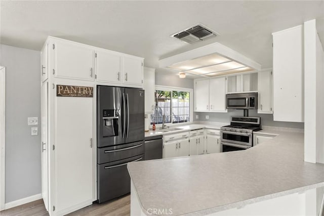 2 Comstock Rd, Chico, CA 95928 - kitchen with appliances with stainless steel finishes, a peninsula, white cabinetry, light countertops, and light wood-type flooring