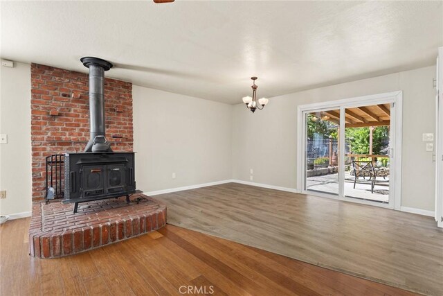 2 Comstock Rd, Chico, CA 95928 - unfurnished living room featuring wood finished floors, a wood stove, baseboards, and a chandelier