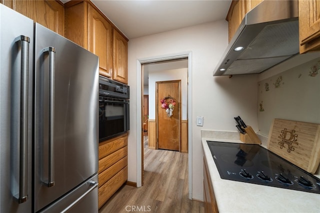 7191 Nixon Dr, Riverside, CA 92504 - kitchen with black appliances, under cabinet range hood, light wood-style flooring, brown cabinetry, and light countertops