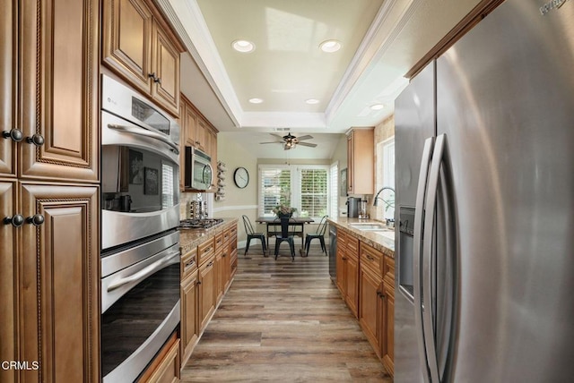 12983 Camden Ct, Moorpark, CA 93021 - kitchen with appliances with stainless steel finishes, a sink, light stone counters, light wood-style floors, and brown cabinets