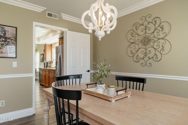 12983 Camden Ct, Moorpark, CA 93021 - dining space featuring crown molding, a chandelier, dark wood-style flooring, and baseboards