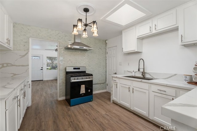 217 N Mcclay St, Santa Ana, CA 92701 - kitchen with stainless steel range with gas cooktop, wall chimney exhaust hood, a sink, wood finished floors, and white cabinets