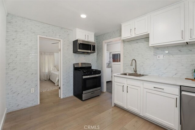 217 N Mcclay St, Santa Ana, CA 92701 - kitchen featuring stainless steel appliances, a sink, white cabinetry, light wood finished floors, and light countertops