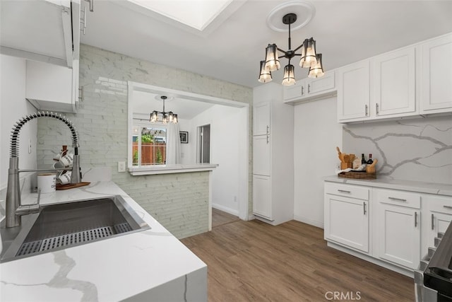 217 N Mcclay St, Santa Ana, CA 92701 - kitchen with a chandelier, a sink, white cabinets, light stone countertops, and backsplash