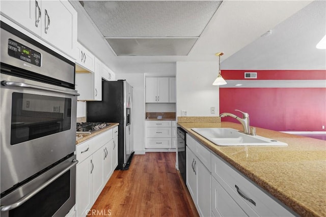 5331 Vallecito Ave, Westminster, CA 92683 - kitchen featuring dark wood-type flooring, white cabinets, appliances with stainless steel finishes, and decorative light fixtures