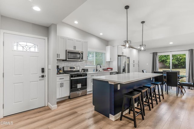 7745 Geyser Ave, Reseda, CA 91335 - kitchen with stainless steel appliances, a kitchen island, light countertops, a kitchen bar, and backsplash