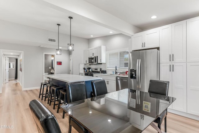7745 Geyser Ave, Reseda, CA 91335 - kitchen featuring appliances with stainless steel finishes, recessed lighting, white cabinetry, light wood-style flooring, and a kitchen breakfast bar
