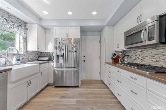 17426 Flanders St, Granada Hills, CA 91344 - kitchen with stainless steel appliances, a sink, white cabinets, backsplash, and light wood finished floors