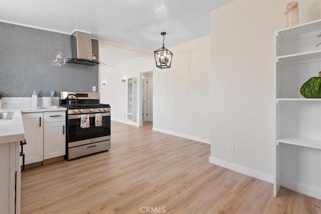 12074 Lee Ave, Adelanto, CA 92301 - kitchen featuring gas range, wall chimney range hood, light countertops, light wood-style floors, and a chandelier