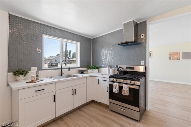 12074 Lee Ave, Adelanto, CA 92301 - kitchen featuring stainless steel gas range oven, a sink, wall chimney range hood, light wood finished floors, and white cabinets