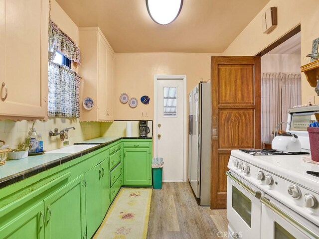 639 Magnolia Ave, Inglewood, CA 90301 - kitchen with refrigerator with ice dispenser, white range with gas cooktop, a sink, light wood-style floors, and tasteful backsplash