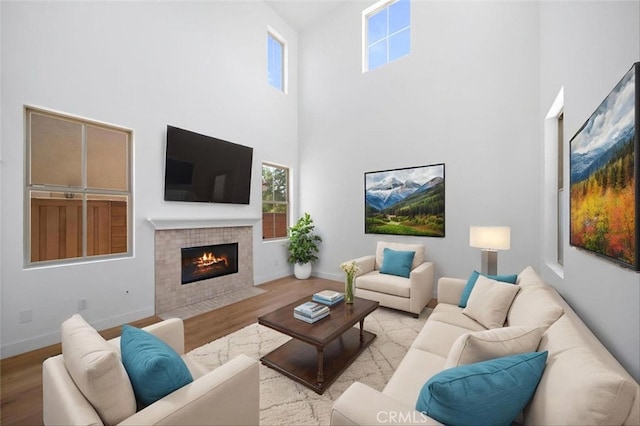 34090 Lady Fern Ct, Lake Elsinore, CA 92532 - living room featuring a towering ceiling, a fireplace, light wood-style flooring, and plenty of natural light