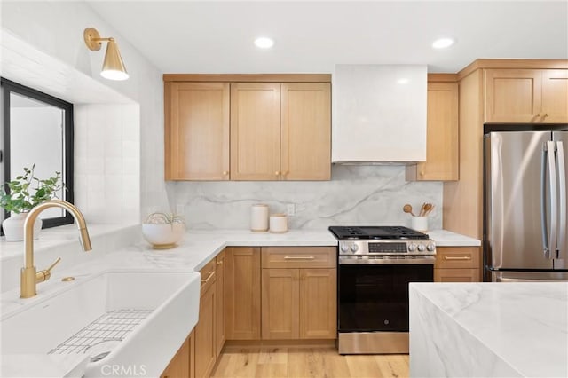 742 Hudson Ave, Costa Mesa, CA 92626 - kitchen featuring appliances with stainless steel finishes, a sink, wall chimney exhaust hood, light wood-style floors, and tasteful backsplash