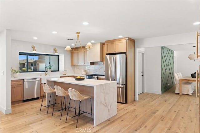 742 Hudson Ave, Costa Mesa, CA 92626 - kitchen featuring appliances with stainless steel finishes, a kitchen island, light countertops, light wood finished floors, and a sink