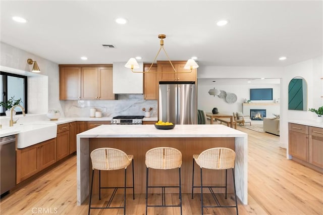 742 Hudson Ave, Costa Mesa, CA 92626 - kitchen with stainless steel appliances, a sink, a kitchen breakfast bar, decorative backsplash, and a kitchen island