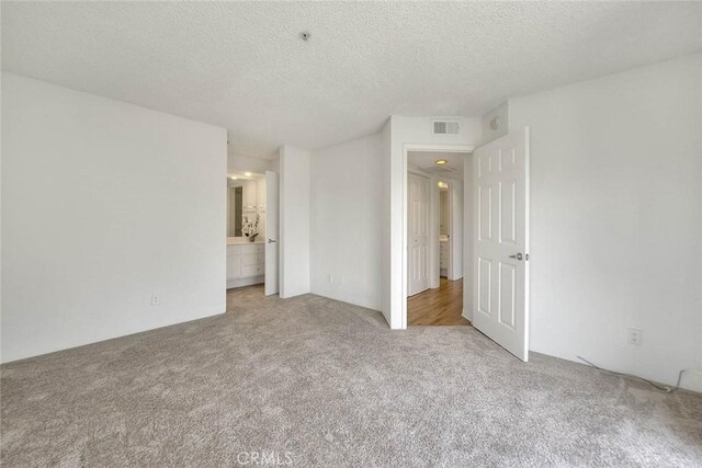 1995 Las Colinas Cir Unit 307, Corona, CA 92879 - unfurnished bedroom featuring carpet, a textured ceiling, and ensuite bath