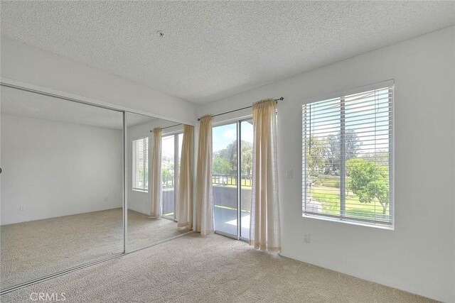 1995 Las Colinas Cir Unit 307, Corona, CA 92879 - unfurnished bedroom featuring access to outside, carpet floors, multiple windows, and a textured ceiling