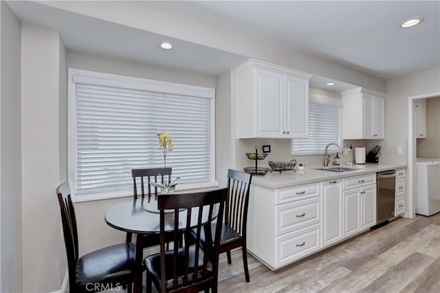 14522 San Feliciano Ln, Mirada, CA 90638 - kitchen with a sink, stainless steel dishwasher, light wood-style flooring, white cabinetry, and washer / clothes dryer