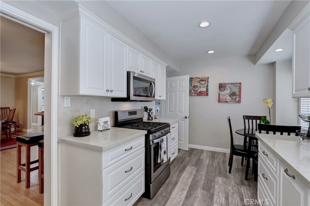 14522 San Feliciano Ln, Mirada, CA 90638 - kitchen featuring appliances with stainless steel finishes, light wood finished floors, recessed lighting, white cabinets, and light stone countertops