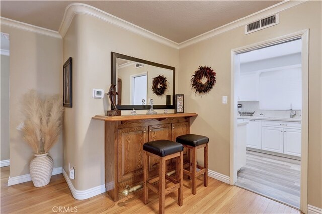14522 San Feliciano Ln, Mirada, CA 90638 - indoor bar featuring light wood-style floors, ornamental molding, and baseboards