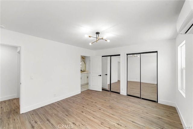 1144311445 Saticoy St, North Hollywood, CA 91605 - unfurnished bedroom featuring a wall unit AC, multiple closets, a chandelier, light wood finished floors, and baseboards
