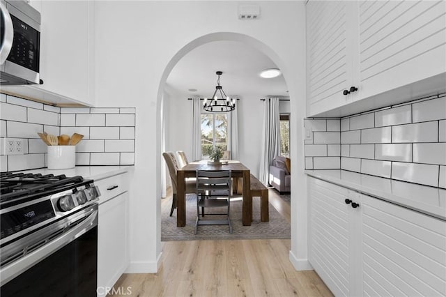 14332 Roblar Pl, Sherman Oaks, CA 91423 - kitchen featuring stainless steel appliances, a chandelier, arched walkways, light wood-type flooring, and light countertops