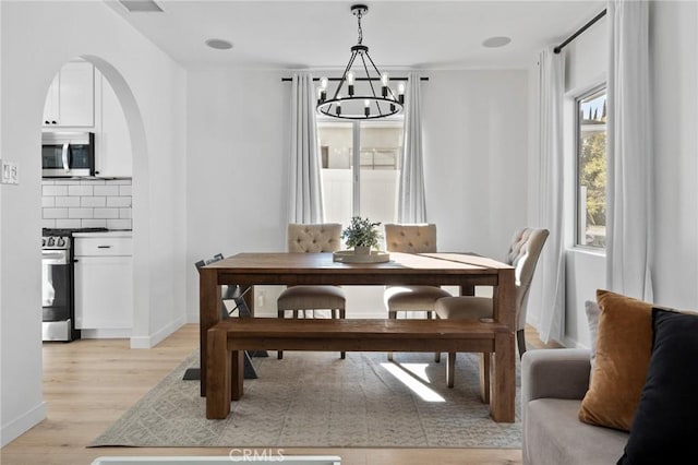 14332 Roblar Pl, Sherman Oaks, CA 91423 - dining room featuring a chandelier, arched walkways, light wood finished floors, and baseboards