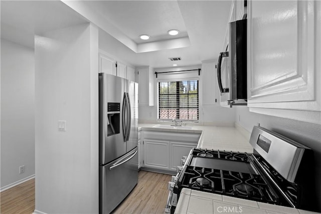 1188 Via Montoya, Camarillo, CA 93010 - kitchen with stainless steel appliances, tile countertops, light wood finished floors, white cabinetry, and recessed lighting