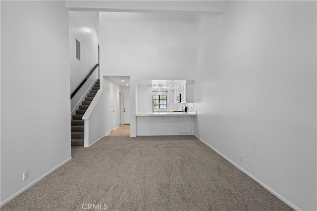 1188 Via Montoya, Camarillo, CA 93010 - unfurnished living room featuring light colored carpet, stairs, baseboards, and a high ceiling